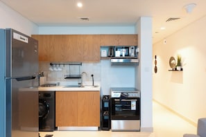 A modern kitchen with stainless steel appliances, wooden cabinets, and a built-in oven. - Bloomfields Studio in Julphar Residence-Reem (Abu Dhabi)