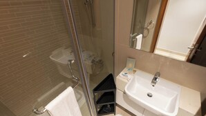 A bathroom with a glass-enclosed shower, a white sink, and a towel rack. - Bloomfields Premium STU Canal View (Abu Dhabi)