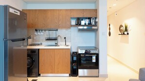 A modern kitchen with stainless steel appliances, wooden cabinets, and a built-in oven. - Bloomfields Premium STU Canal View (Abu Dhabi)