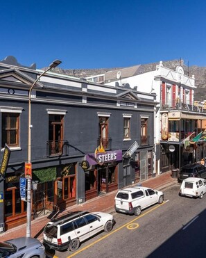 A street view with a building featuring a 'Steers' sign, parked cars, and a clear sky.