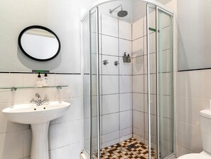 A bathroom with a glass-enclosed shower, a white sink, and a mirror.