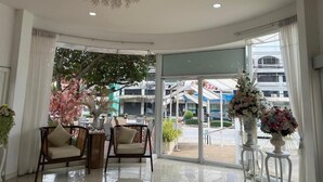 Un vestíbulo con candelabro, zona de estar y ventanas amplias con vistas al exterior.