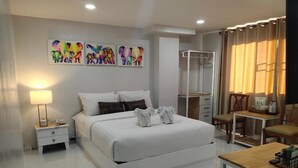 Un dormitorio moderno con una cama grande, mesitas de noche, un armario, un escritorio y una silla.