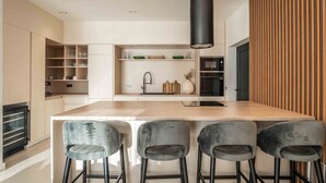 A modern kitchen with a central island, bar stools, and built-in shelves.