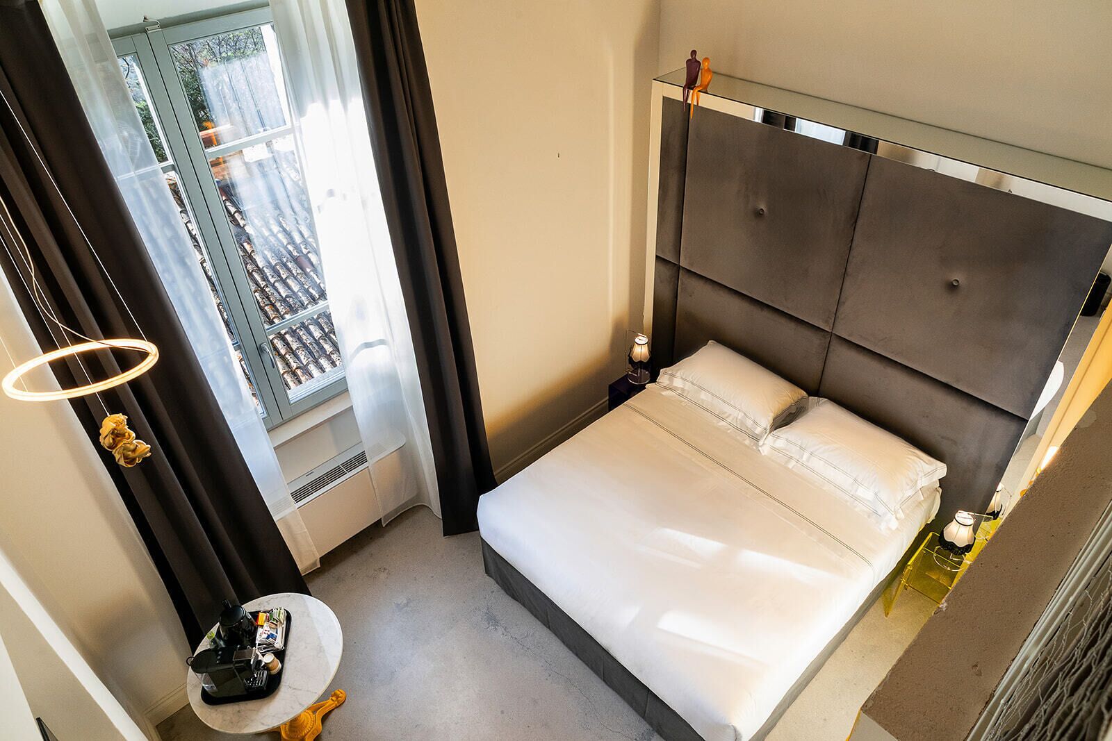Une chambre d’hôtel moderne avec un grand lit, une petite table de chevet, un minibar et une vue sur l’extérieur.
