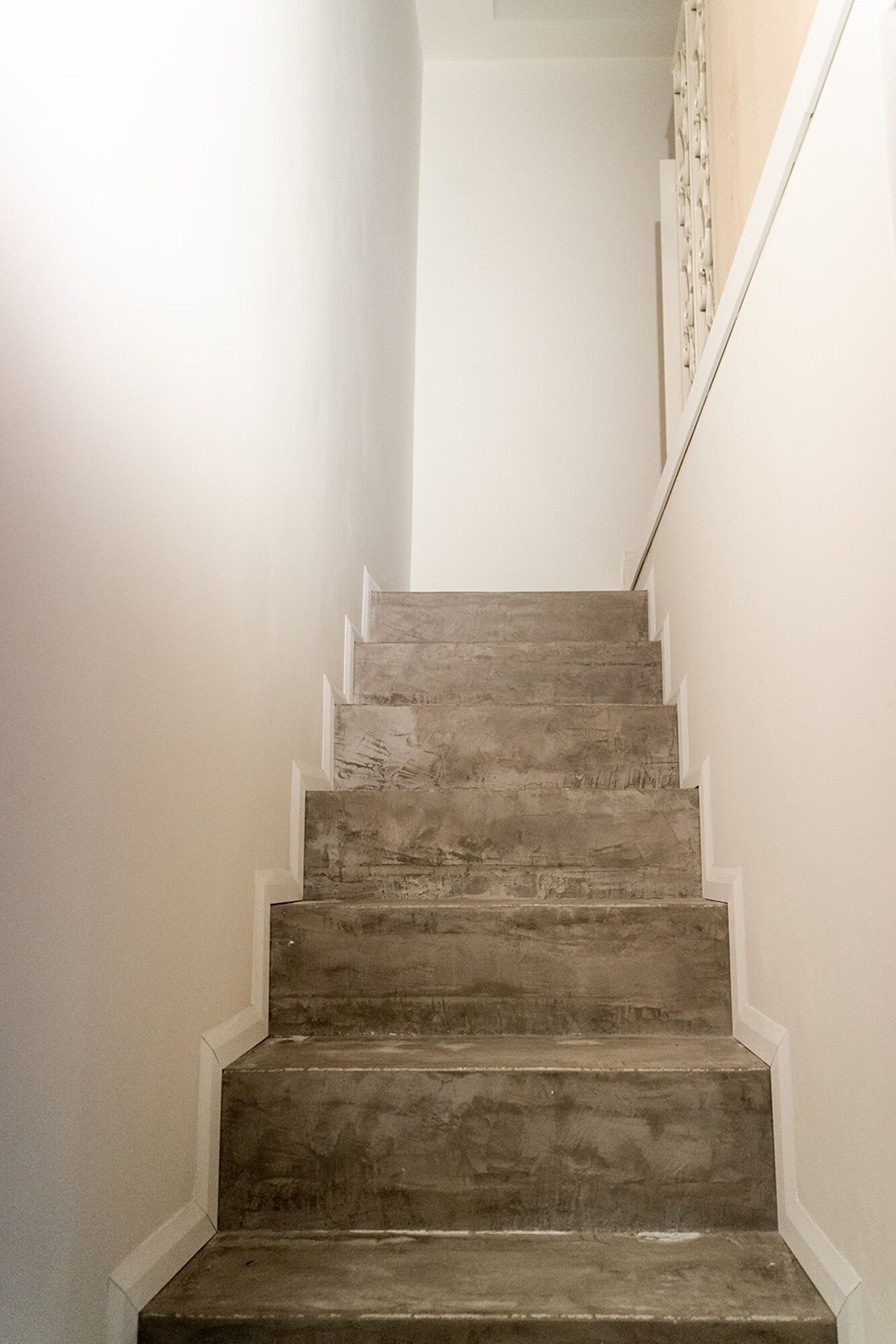 Una escalera con detalles de madera, paredes blancas y barandilla blanca.