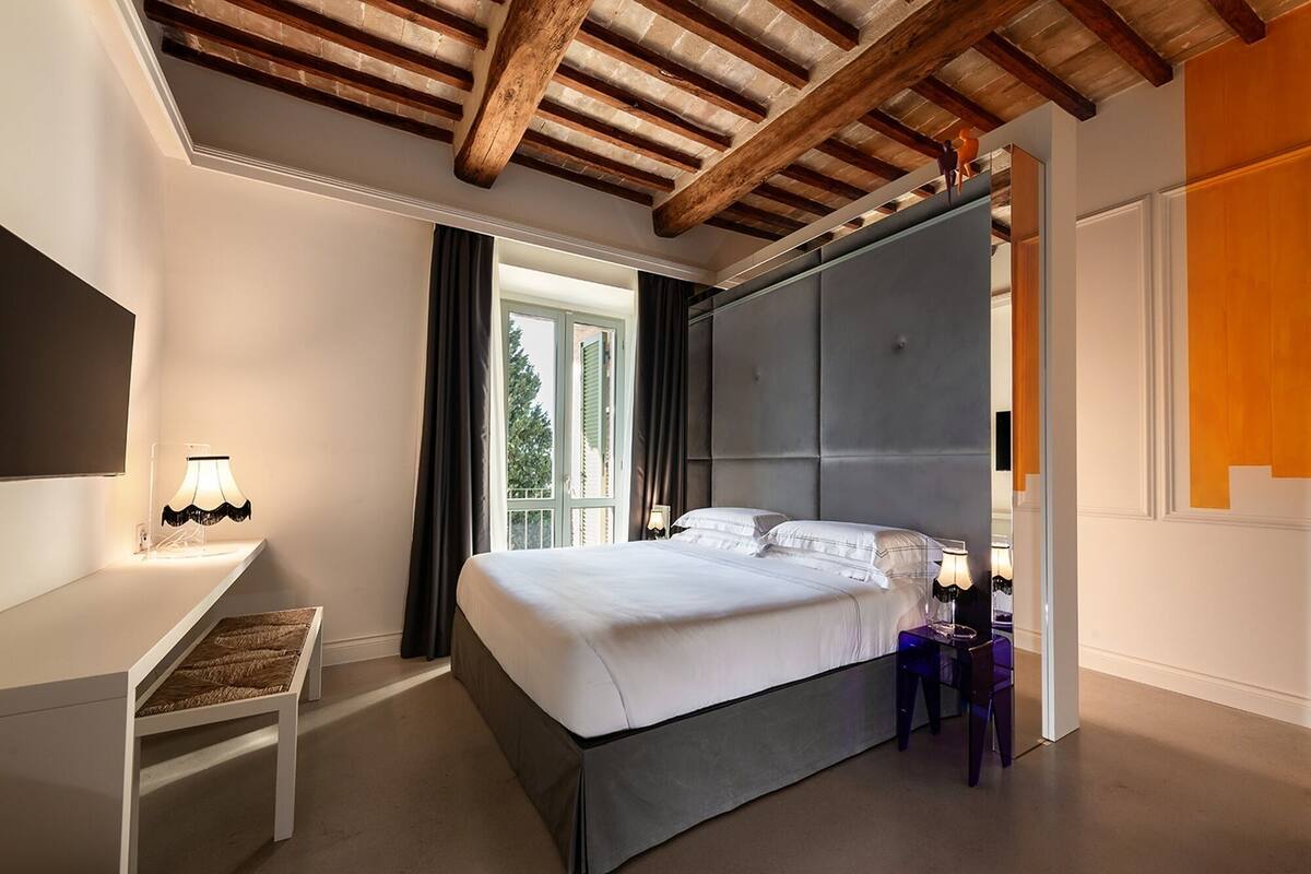 A bedroom with a bed, bedside tables, a desk, and a window with curtains.