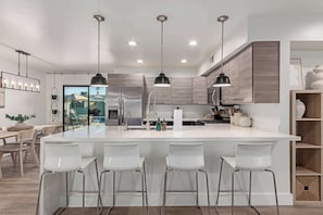 Una cocina moderna con una isla central, electrodomésticos de acero inoxidable e iluminación colgante.