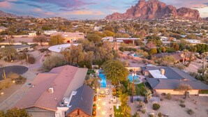 An aerial view of a residential area with houses, a swimming pool, and a mountain in the background. - Palo Verde Experience|Zen-Inspired Resort Oasis (Phoenix)