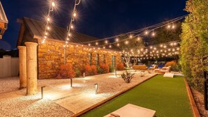 A stone building with a patio area, outdoor seating, and a green lawn. - Palo Verde Experience|Zen-Inspired Resort Oasis (Phoenix)