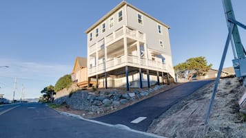 Un bâtiment à deux étages doté d’un balcon à l’étage supérieur, situé sur une colline, avec une route dégagée devant.