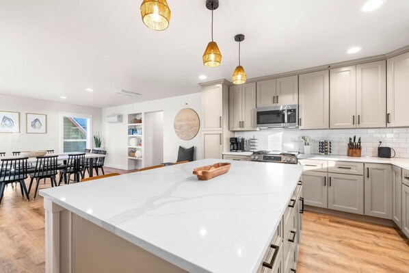 Una cocina moderna con armarios blancos, una isla grande e iluminación colgante.