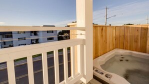 En balkon med et træhegn, en jacuzzi og udsigt over et boligområde.