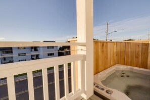Un balcon avec une balustrade en bois, un jacuzzi et une vue sur un quartier résidentiel.