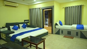 Ein Hotelzimmer mit einem gro ßen Bett, einem kleineren Bett, einer Couch, einem Tisch und einer Klimaanlage.
