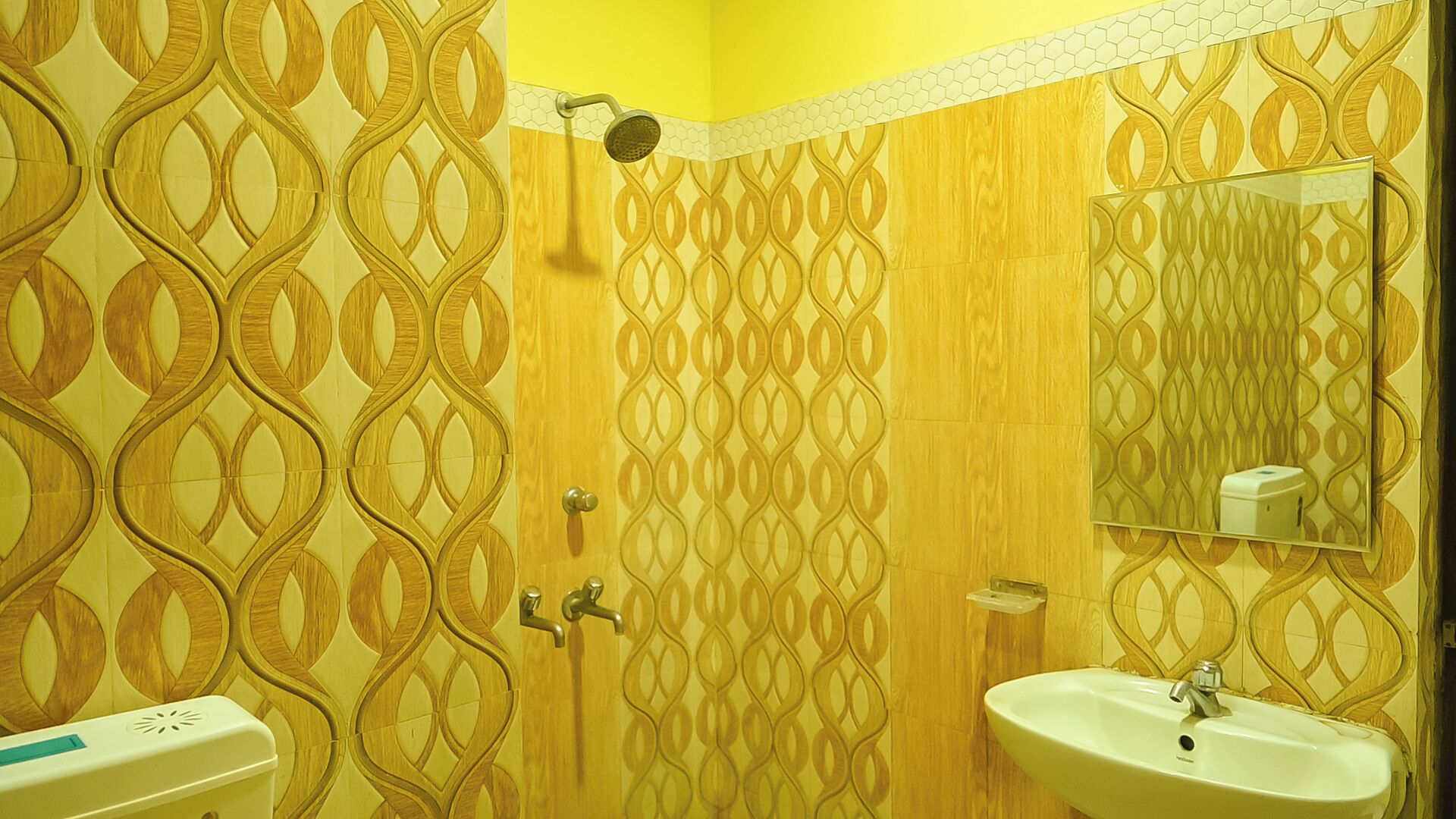 A bathroom with a patterned tile wall, a sink, and a mirror.