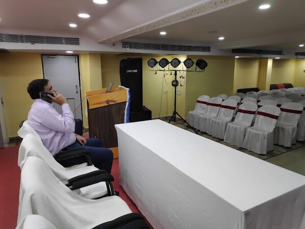 A conference room with a long table, rows of chairs, a podium, and a speaker system. - HOTEL M PLAZA DIGHA (Kanthi)