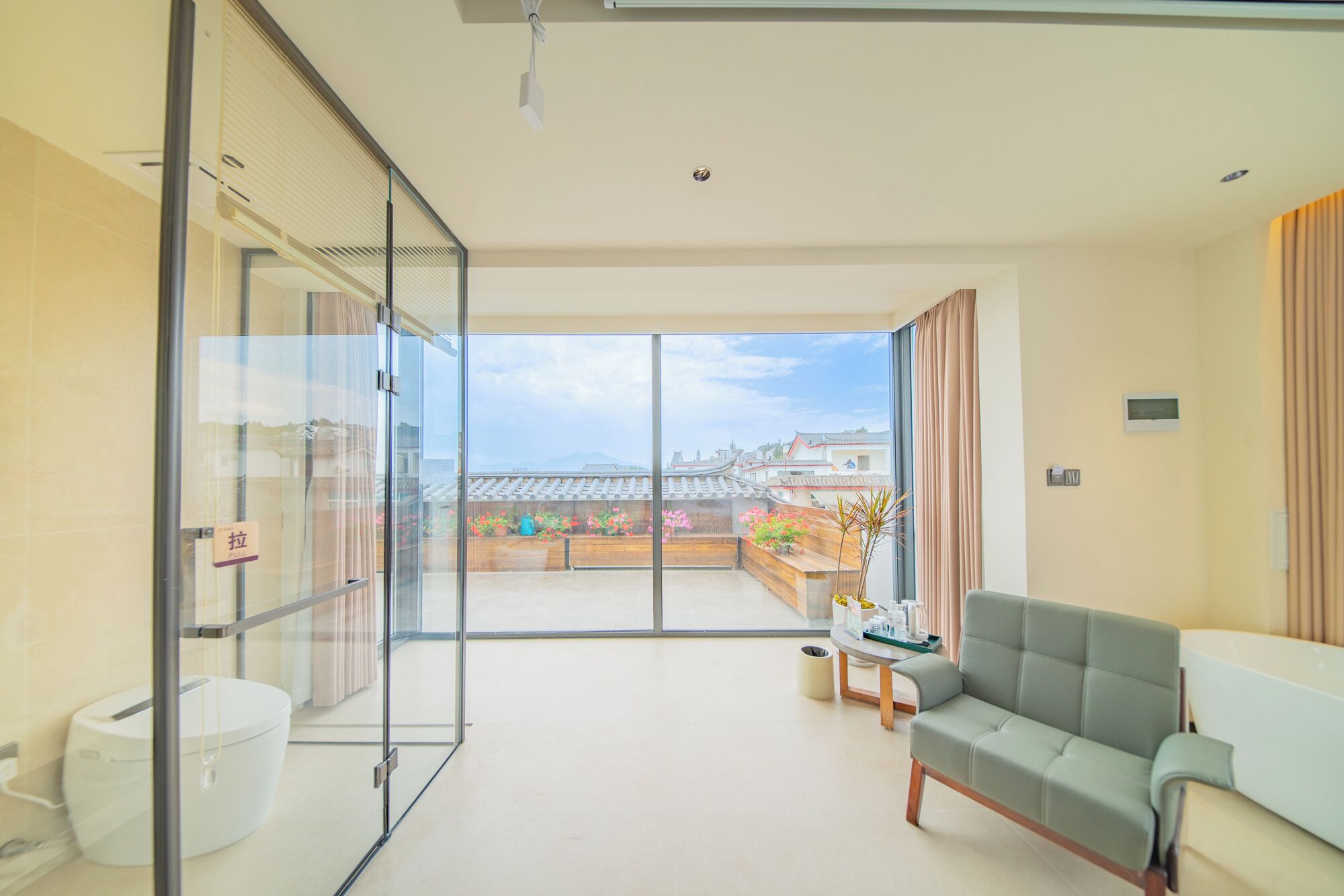 A modern hotel room with a balcony, a sofa, and a view of traditional buildings.