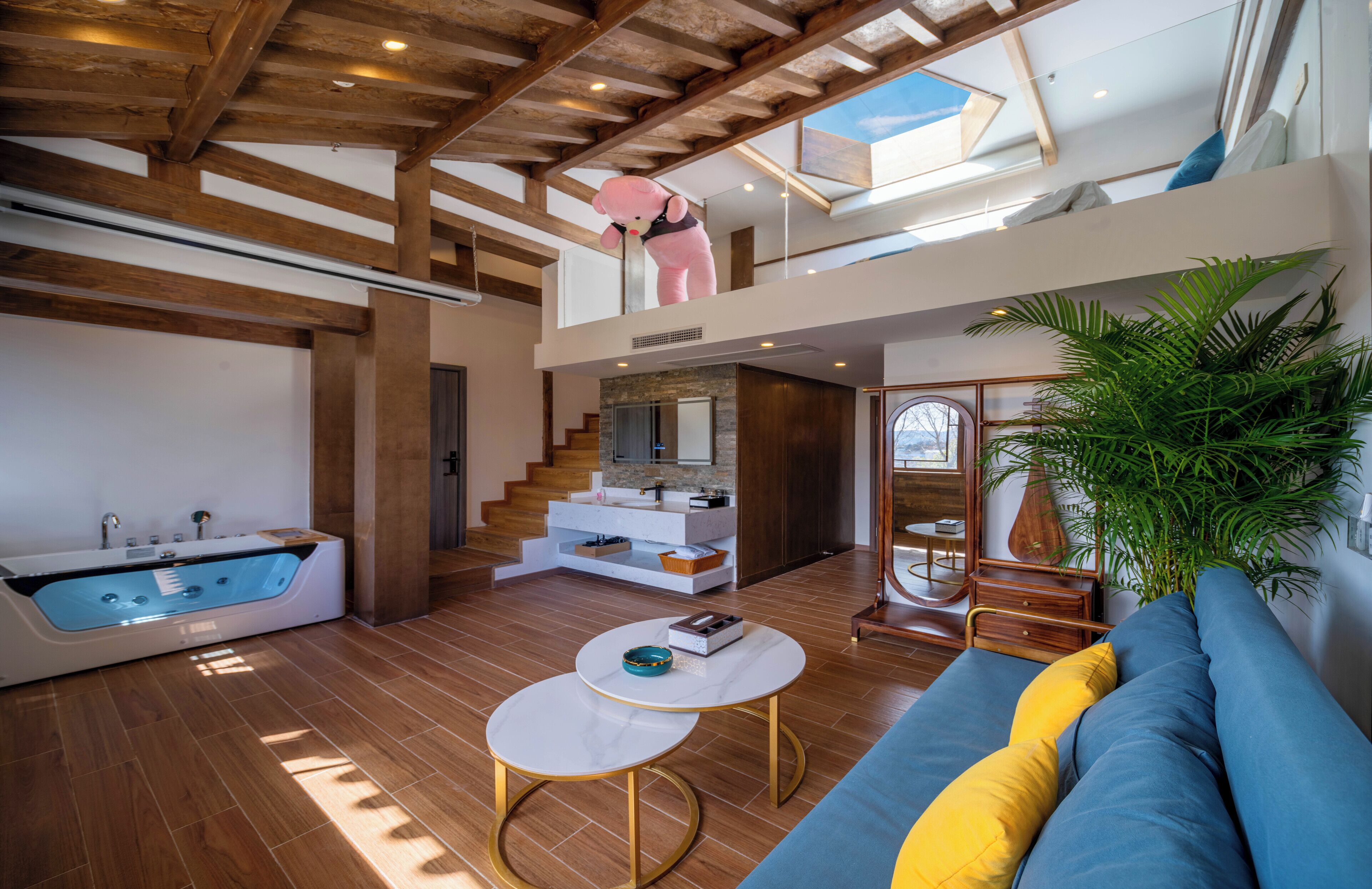 A spacious living area with a large bathtub, a staircase leading to an upper level, and a cozy seating area with cushions.