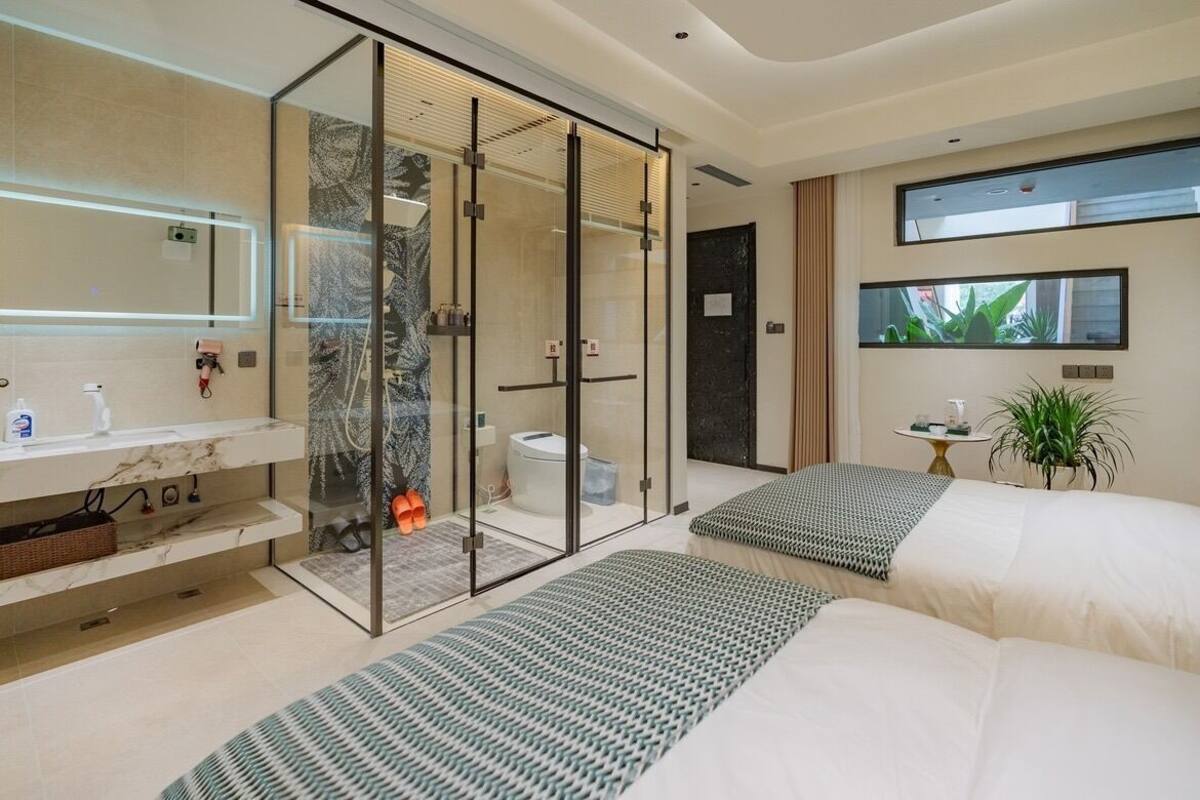 A modern bathroom with a glass shower enclosure, a toilet, and a sink with a marble countertop.