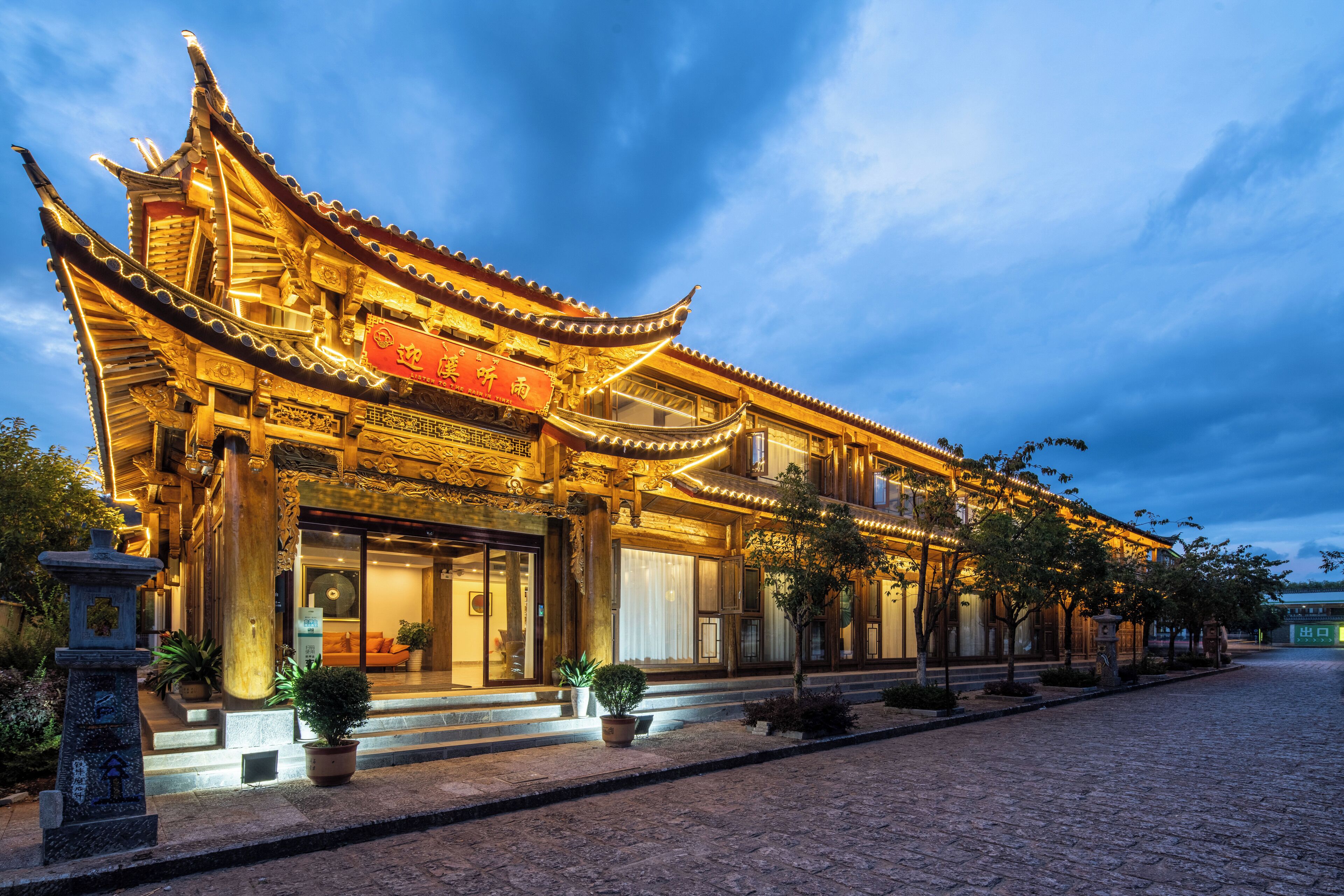 A traditional Chinese building with ornate architecture, a signboard, and potted plants in front.