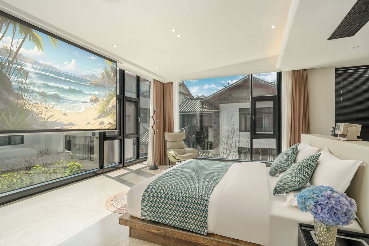 A modern bedroom with a large bed, a view of the beach, and a balcony.