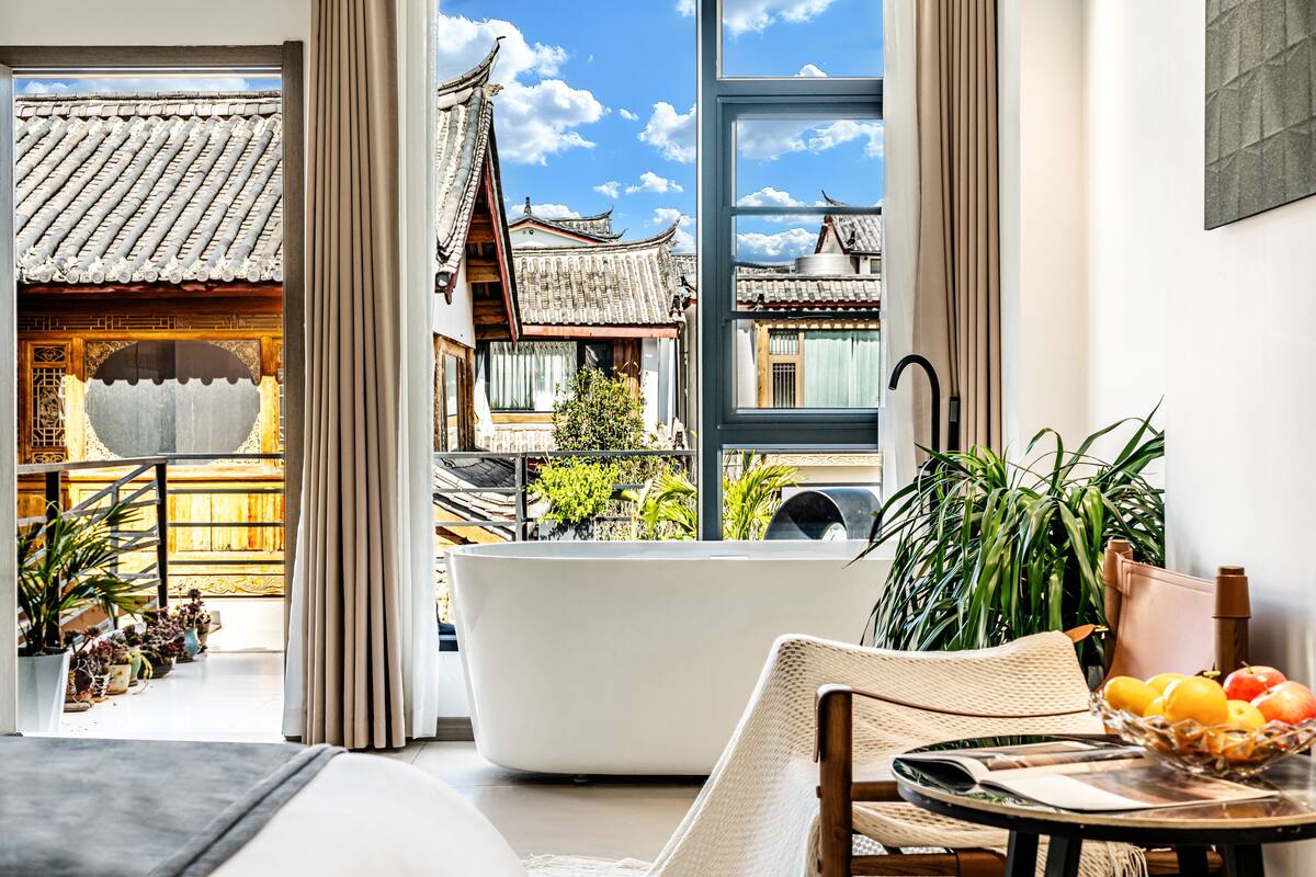 A modern interior with a large window, a bathtub, wicker furniture, and a fruit bowl.
