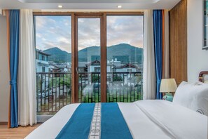 A hotel room with a large bed, a view of traditional buildings, and a balcony with a metal railing. - Gucheng district ying Xi ting Yu inn (Lijiang)