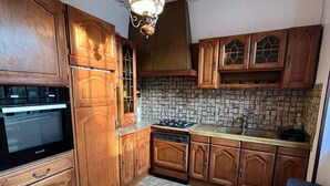 A kitchen with wooden cabinets, a tiled backsplash, and a hanging light fixture. - Appartement à Sevran (Sevran)