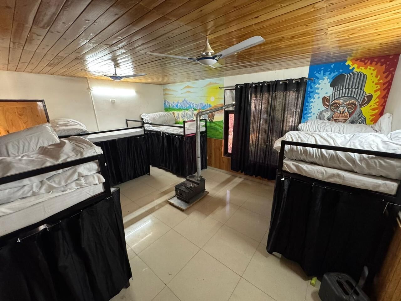 Un dormitorio con camas literas, ventilador de techo, calefactor y un mural en la pared.