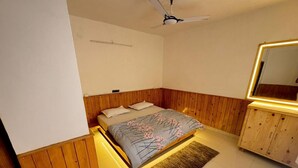 Ett sovrum med en säng, träpanel på väggarna, en takfläkt, en spegel och ett skåp med belysning.