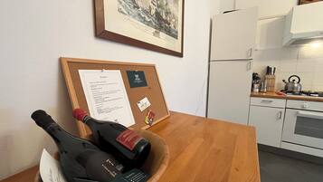 Eine Pinnwand mit einem gerahmten Gemälde, ein Schwarzes Brett mit einer Speisekarte und ein Holztisch mit Flaschen und einer Speisekarte.