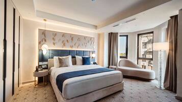 Een moderne hotelkamer met een groot bed, een zithoek, een bureau met lamp en uitzicht op de stad.