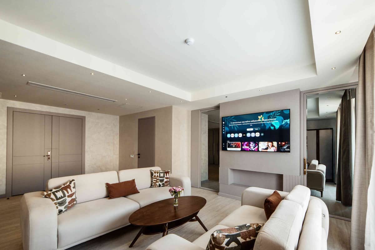 A modern living room with a flat-screen TV, two sofas, a coffee table, and a door leading to another room.