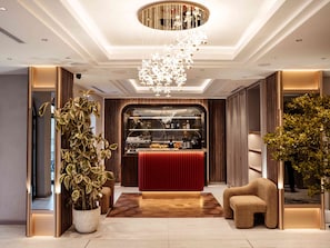 A modern lobby with a reception desk, a chandelier, and potted plants. - Meridian Luxury Boutique Hotel (Baku)