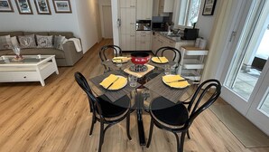 Un coin repas avec une table ronde, des chaises noires et un pot rouge posé sur la table.