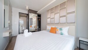 Habitació d'hotel moderna amb un llit gran, un armari encastat, un mirall i una taula de nit.