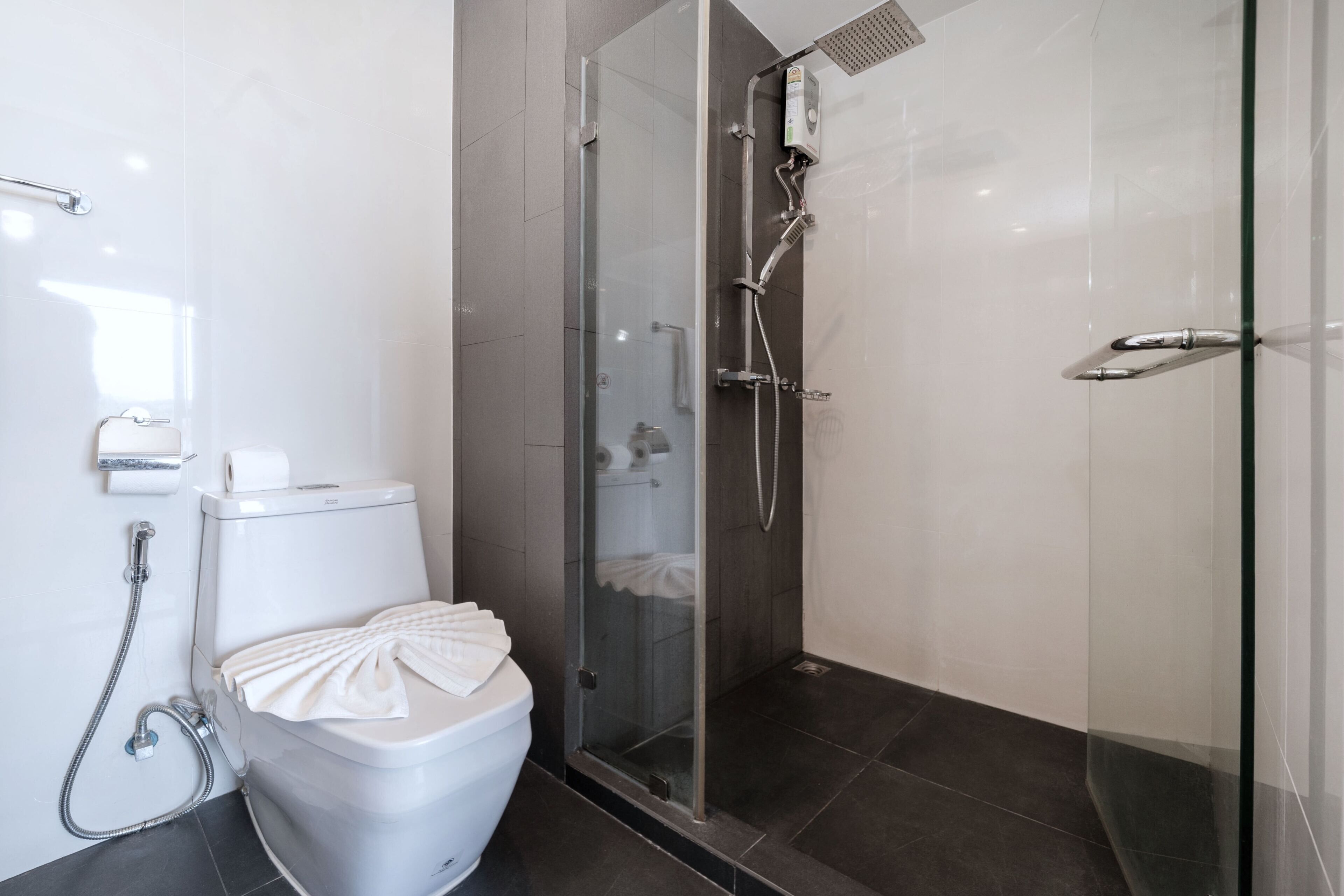 A modern bathroom with a toilet, a glass shower enclosure, and a glass door.