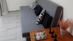 A modern living room with a grey sofa, black and white patterned pillows, a wooden coffee table with decorative items, a wall clock, and a geometric art piece.