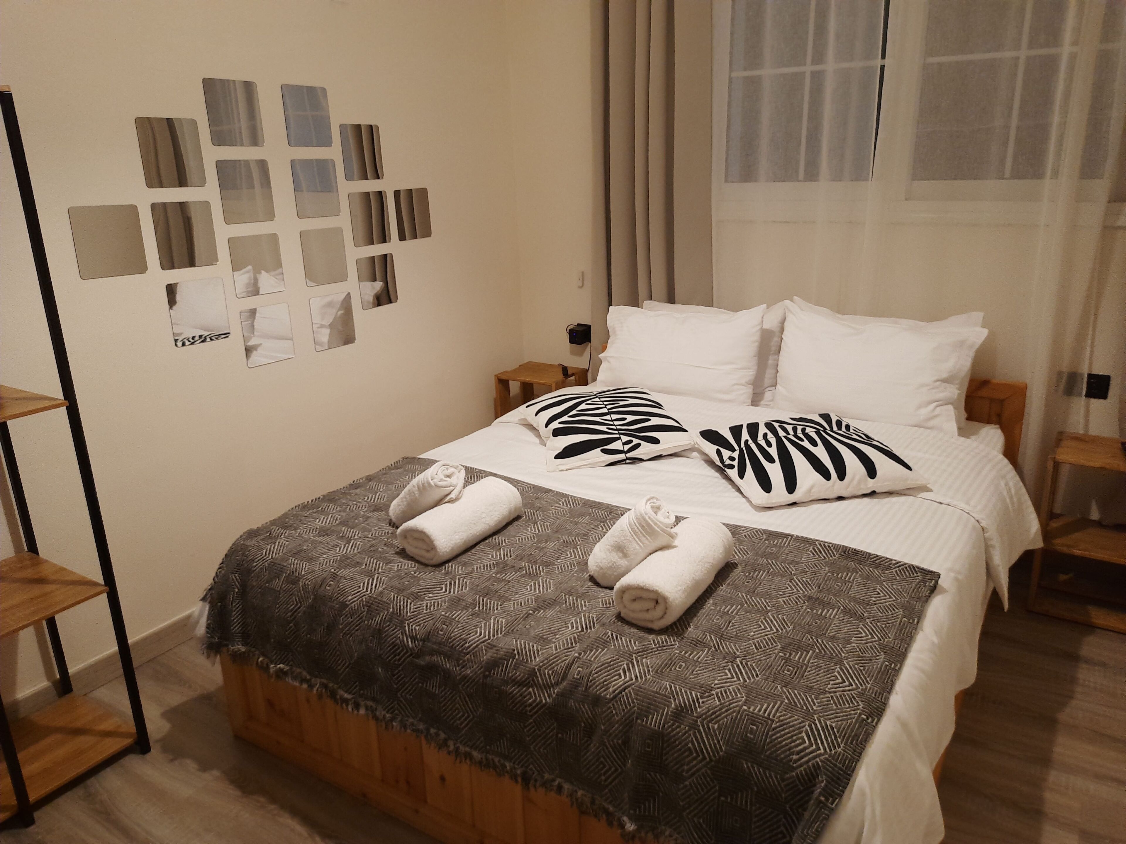 Un lit bien fait, recouvert d’une couverture à motifs, avec deux oreillers à imprimé zébré et deux serviettes enroulées posées sur le lit.