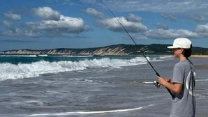 A person fishing by the sea with a clear sky and distant hills. - Welcome to "Bay 13" The Perfect Family Retreat with Inground Pool (Tin Can Bay)