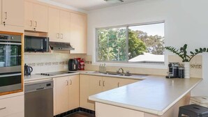 A modern kitchen with a large window, stainless steel appliances, and light-colored cabinetry. - Welcome to "Bay 13" The Perfect Family Retreat with Inground Pool (Tin Can Bay)