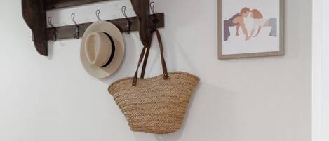 A wall-mounted wooden shelf with a hat and a woven basket hanging from it.