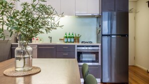 A modern kitchen with a wooden dining table, a built-in oven, a stainless steel refrigerator, and a potted plant on the counter. - StayCentral - Brunswick Loft - Michael Street, Brunswick - 1 Bedroom, 1 Bed, 1.5 bathroom, 1 Parking, Pet Friendly (Brunswick)