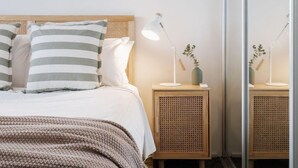 A neatly made bed with striped pillows, a bedside lamp, and a small plant on a wooden nightstand. - StayCentral - Brunswick Loft - Michael Street, Brunswick - 1 Bedroom, 1 Bed, 1.5 bathroom, 1 Parking, Pet Friendly (Brunswick)