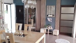 A modern living room with a dining area, a small table with plants, and a large window with curtains. - Room at Sylvie's, breakfast included (Val-d'Izé)