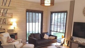 A modern living room with a sofa, armchair, ottoman, and a coffee table. - Room at Sylvie's, breakfast included (Val-d'Izé)