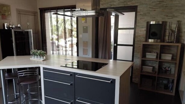A modern kitchen with a central island, bar stools, and a built-in oven. - Room at Sylvie's, breakfast included (Val-d'Izé)