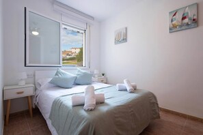 Une chambre d’hôtel avec un lit, une table de chevet, une fenêtre et un tableau au mur.
