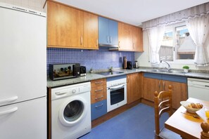 A compact kitchen with a washing machine, a microwave, and a sink.